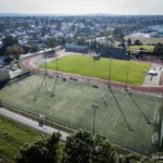 Boisko a w tle bieżnia i stadion lekkoatletyczny